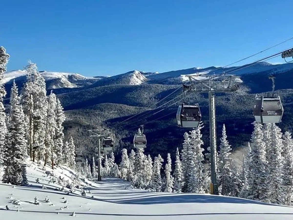 This image features ski lift gondolas gliding above snow-covered trees with a majestic mountain range as the backdrop, embodying the winter adventure vibe. The snow-laden landscape and modern lifts evoke the thrill of skiing or snowboarding at a world-class resort.