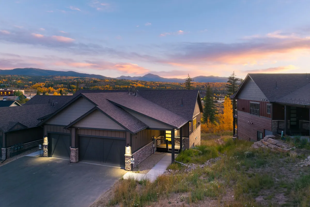 A modern exterior with sleek architectural lines opens to a landscaped entrance, set against a dramatic mountain backdrop. The setting exudes tranquility, inviting visitors to explore the connection between home and nature.