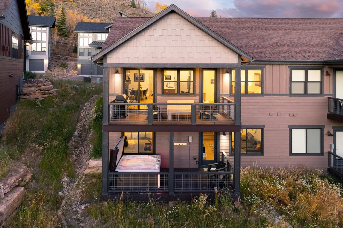 A serene exterior shot of the chalet’s balconies and large windows, surrounded by natural beauty. The inviting balconies offer space for relaxing and socializing while enjoying the view of the surrounding nature.