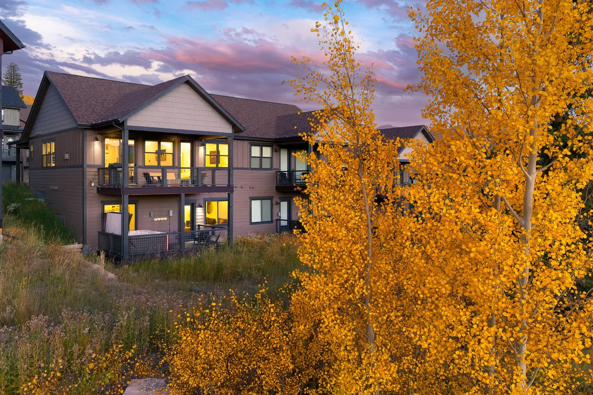 An exterior view capturing balconies adorned with autumn leaves, set against a sunset sky. The scene is peaceful and inviting, hinting at cozy evenings spent outdoors and easy access to nature walks.