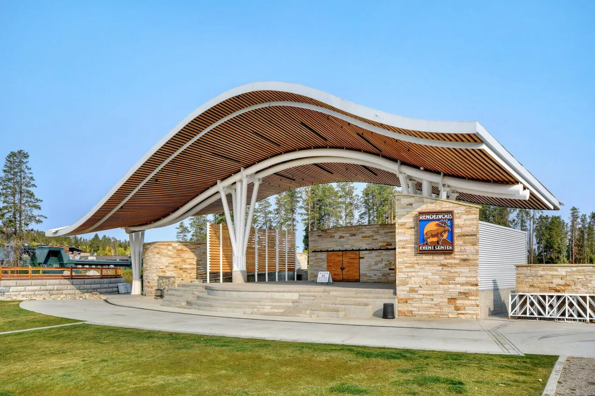 An exterior view of an event center with a modern curved roof and stone walls. The venue is marked by an 'event center' sign, indicating a space where community gatherings, live music, and seasonal festivals take place—echoing the downtown's cultural attractions.