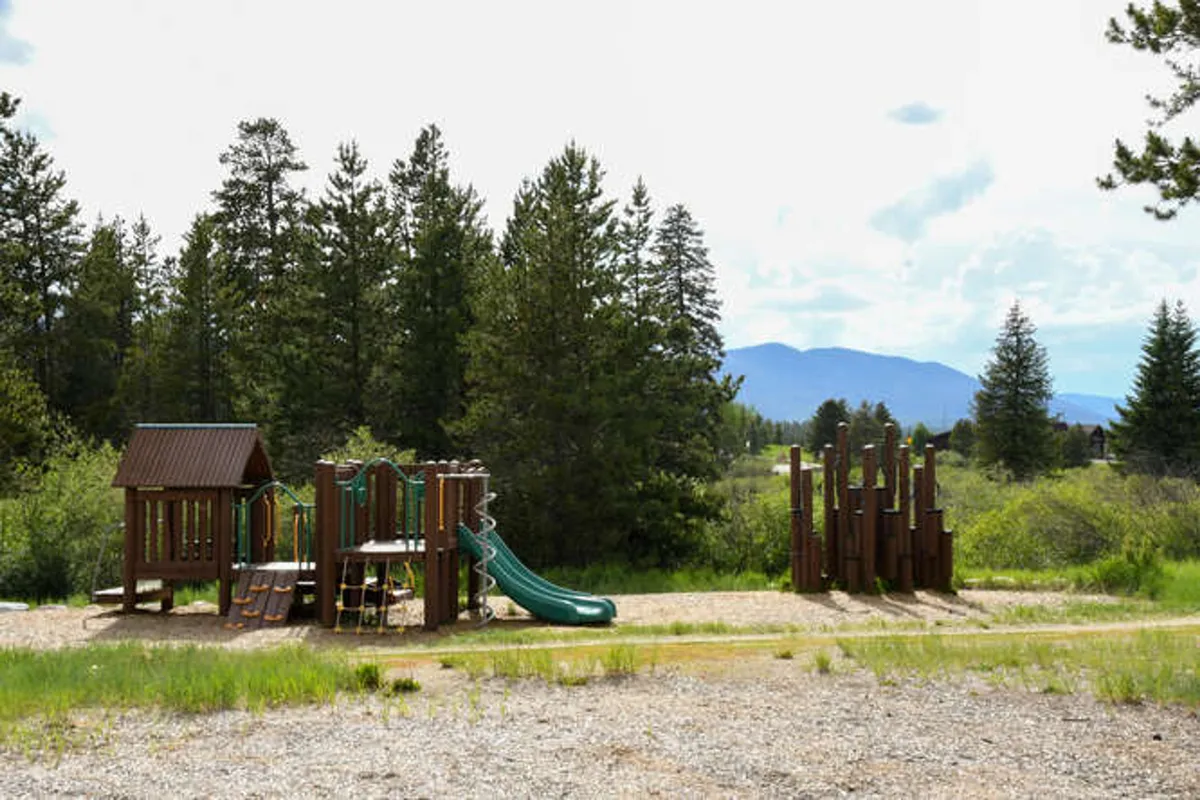 An exterior view of a colorful playground with slides and climbing features, set in a cheerful outdoor environment. Children are seen playing energetically while families gather around for picnics and quality time.